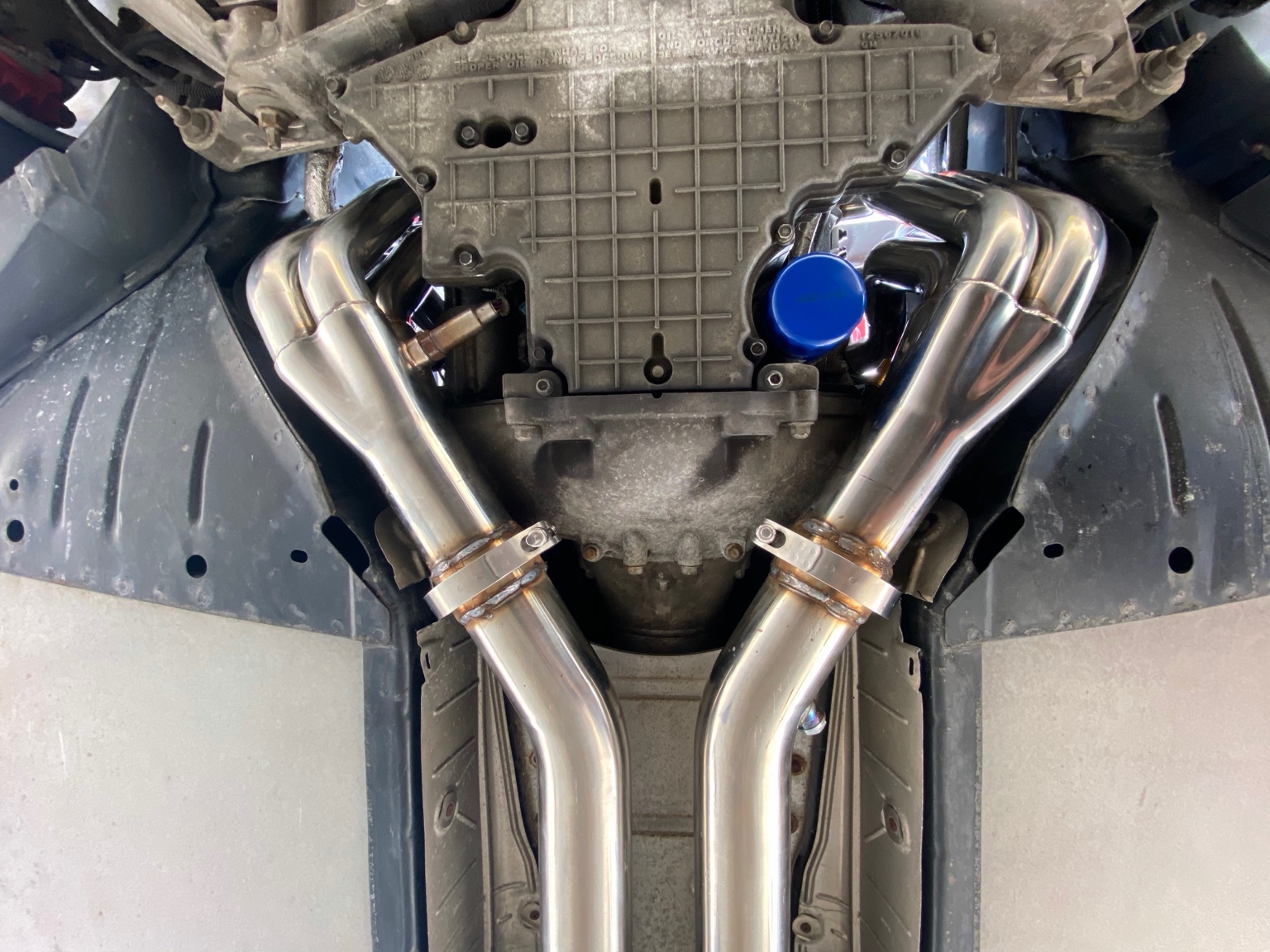 Underside of a vehicle showing fitted stainless exhaust headers and welded pipe connections