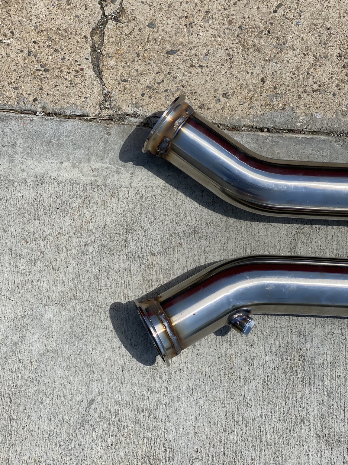 Two stainless exhaust pipes with welded flanges and a sensor bung
