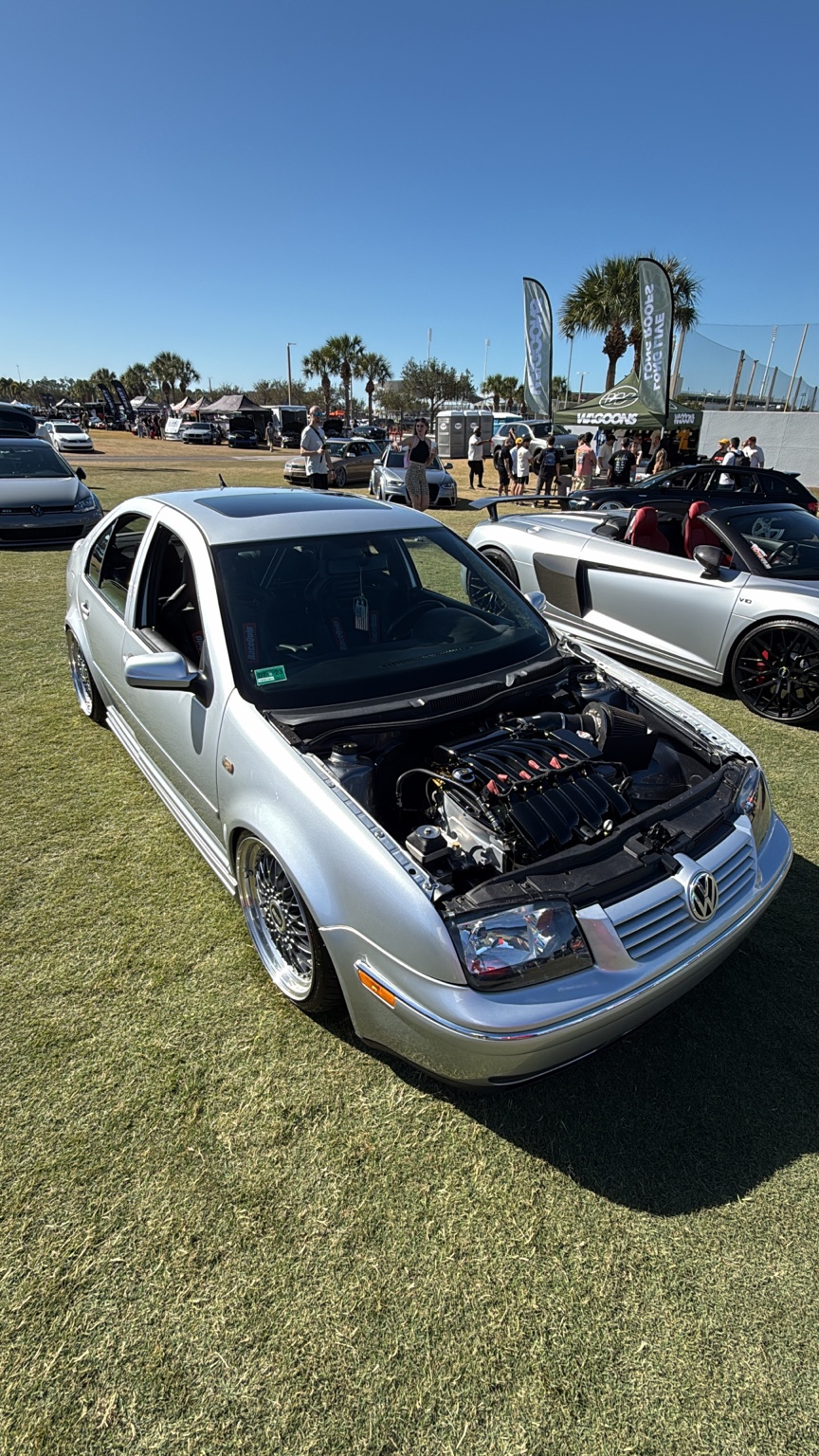 Silver Volkswagen Jetta at a car show displaying its shaved engine bay